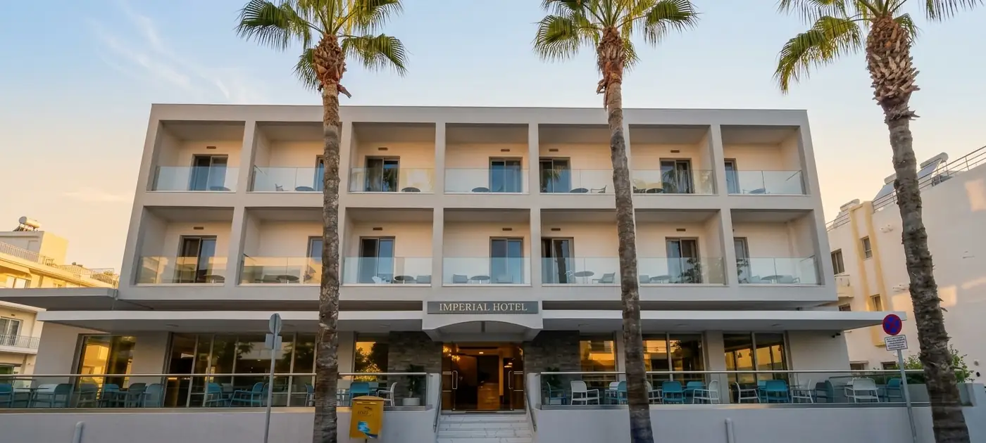 Η αναβαθμισμένη όψη του Imperial Hotel στο σούρουπο, ανάμεσα στους φοίνικες